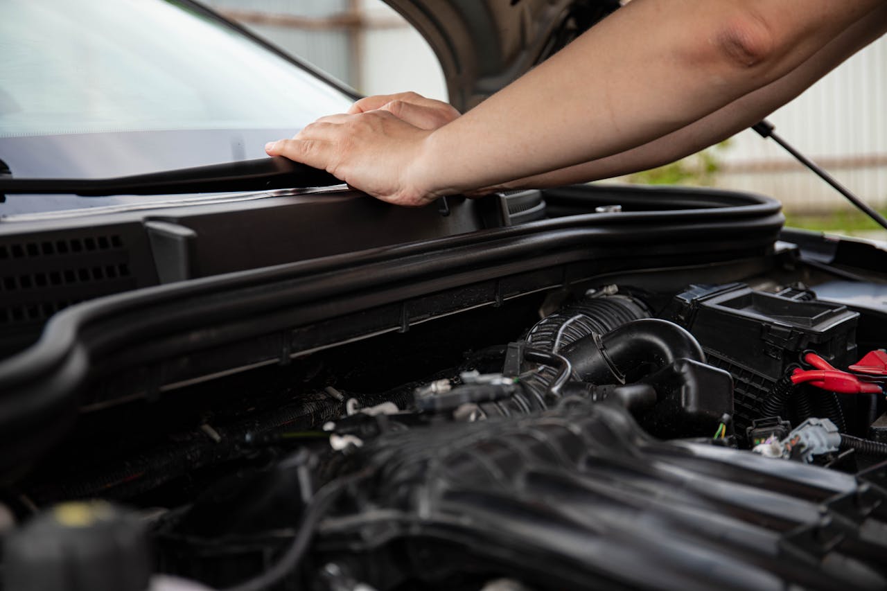 Close-up of hands working on car engine. Detailed view of automotive repair.